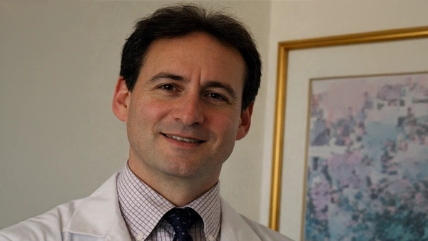 Jeffrey Bernstein wearing a white lab coat and a checkered dress shirt with a dark tie